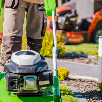 Lawn & Garden RentalsIndividual pushing a push mower with a riding mower in the background